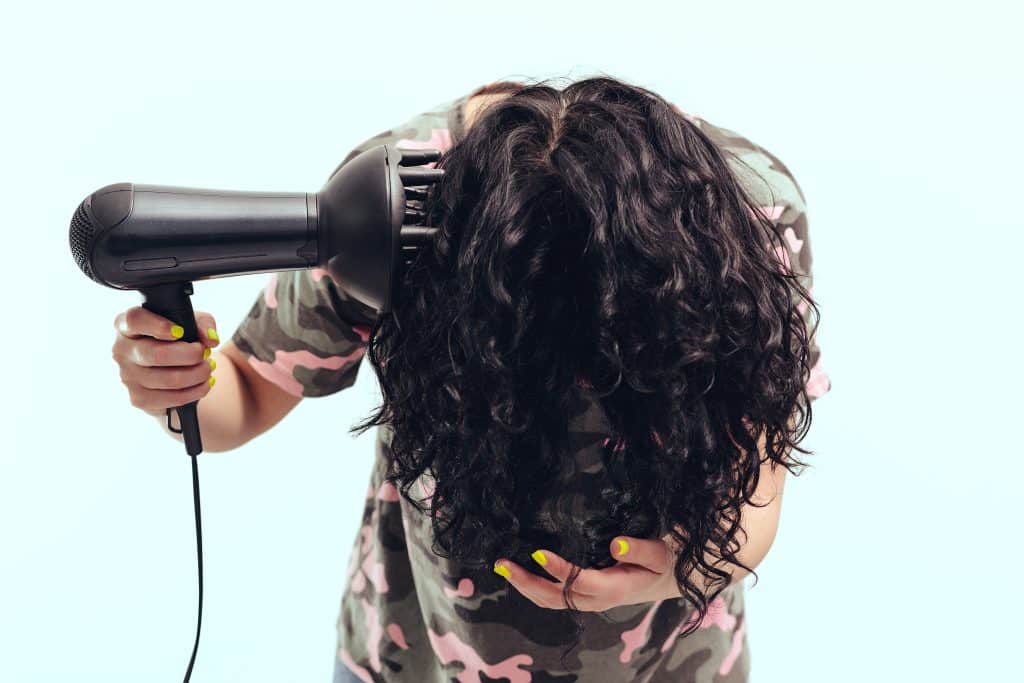 woman flipped over diffusing her curly hair upside down