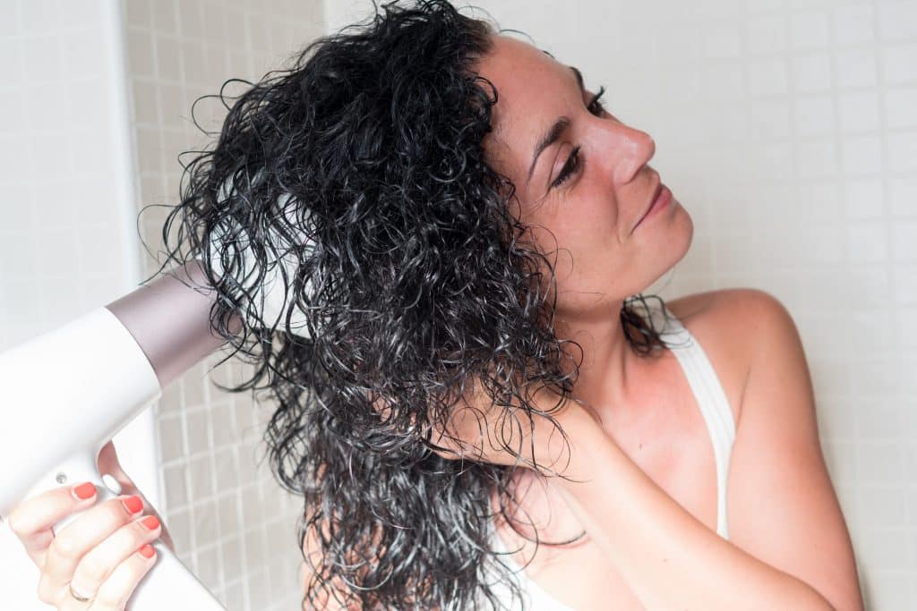 woman diffusing her curly hair after washing