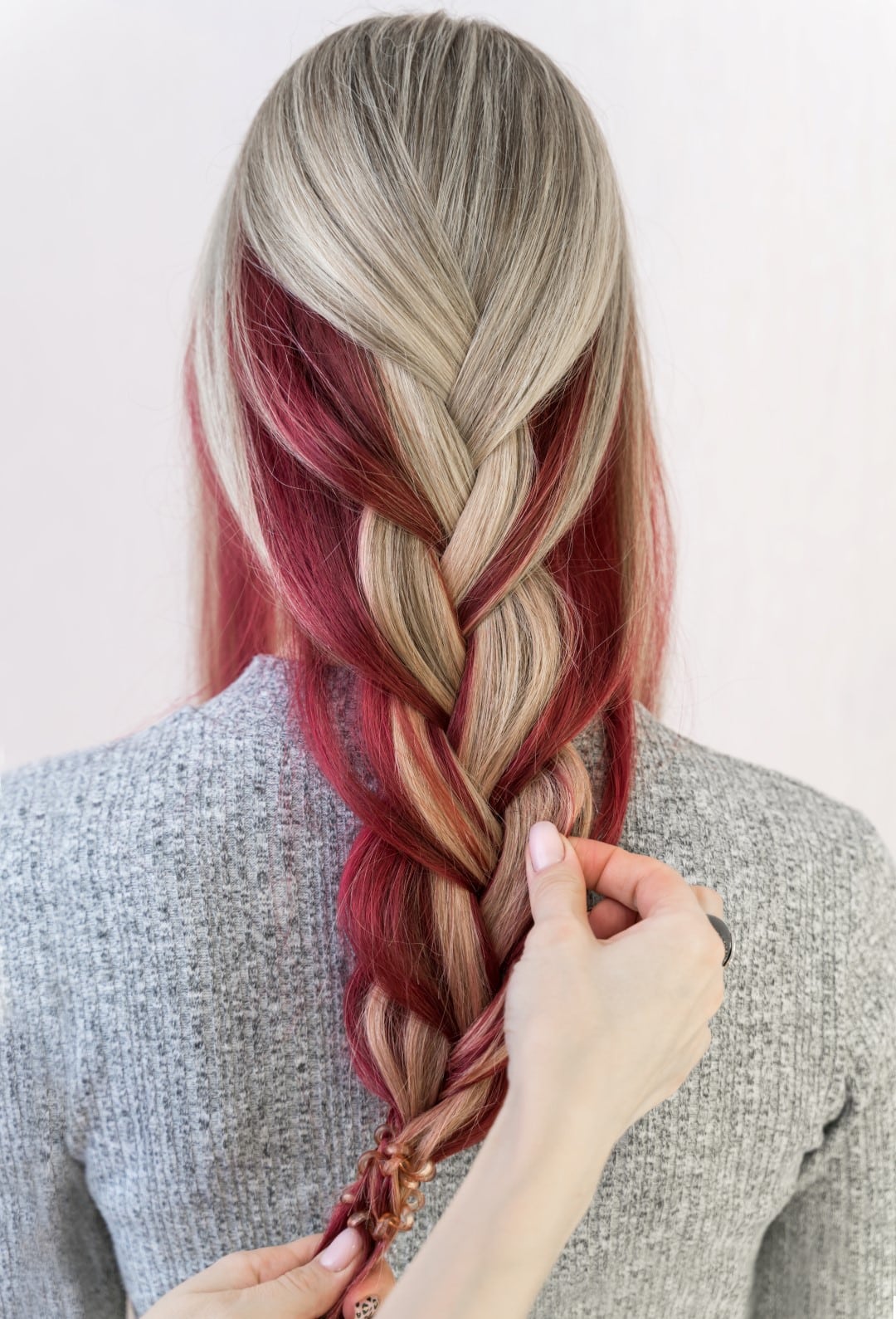 Red color blocking in blond hair pulled into a braid