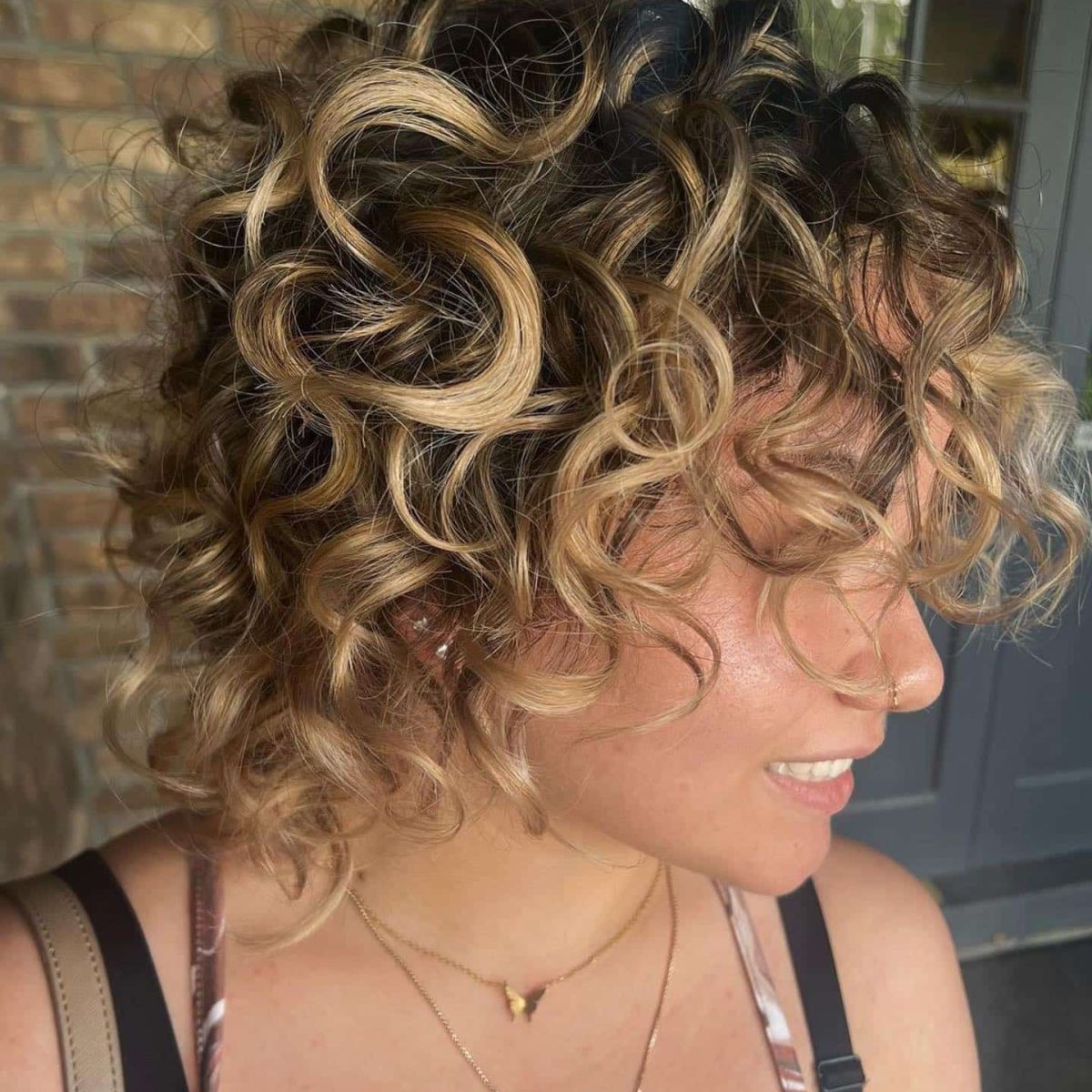 Woman with curly hair and new balayage coloring.